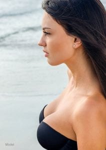 Profile headshot of young adult female model on a beach with a voluptuous chest