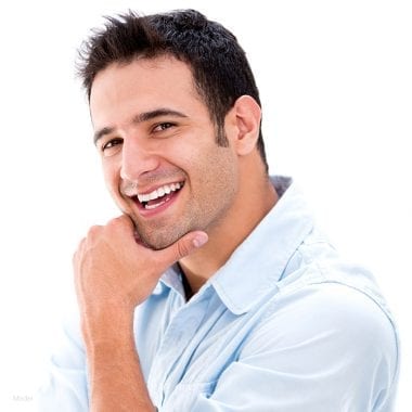 Headshot of a smiling male model in a blue shirt holding his chin in his hand