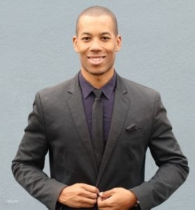 Male model in a black suit buttoning up his jacket