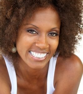 Headshot of an adult female model in a white tank smiling with full cheek bones