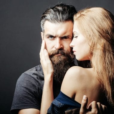 Woman touching a stern mans beard