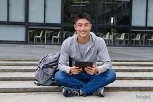 Young man sitting on stairs with a tablet