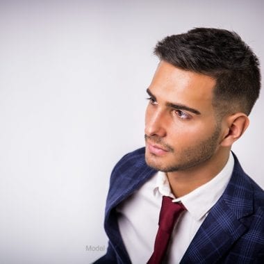 Arial profile shot of a young adult male model in a suit with a full set of hair