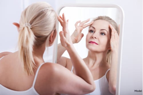 beautiful middle aged lady looking in the mirror thinking about getting the Millennial Face Lift-img-blog