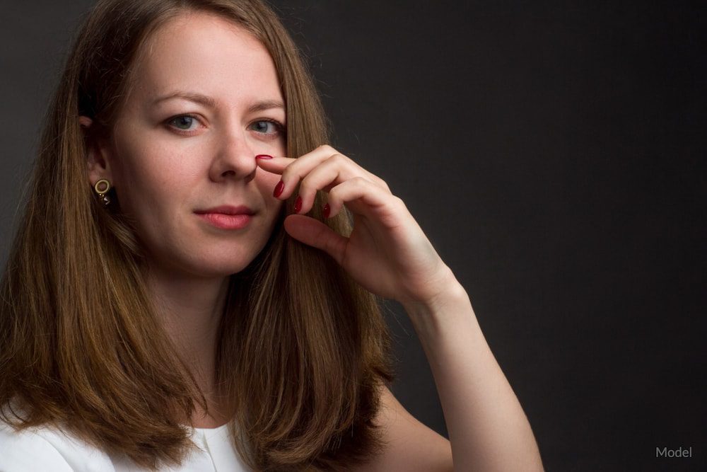 Women pointing to her nose, showing a rhinoplasty concept.